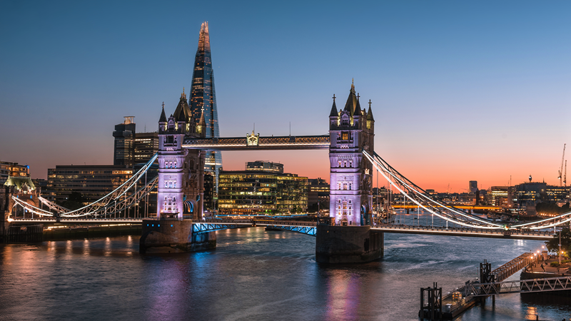 Tower Bridge lit up at night with the Shard visible in the background, showcasing London's iconic skyline.