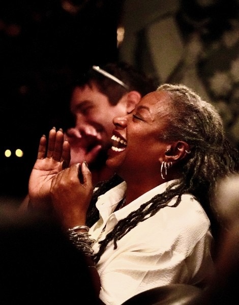 Guest laughing and enjoying a magical performance in a cozy, intimate setting, as part of a comedy and magic show.